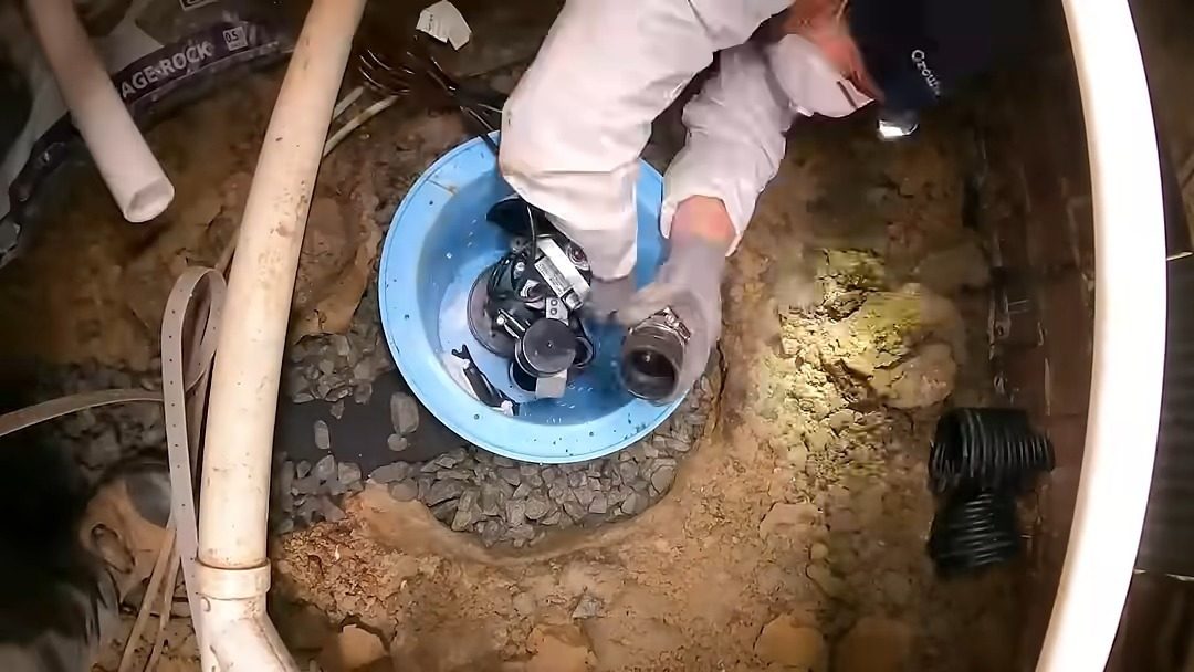 Technician installing a sump pump basin in a crawl space