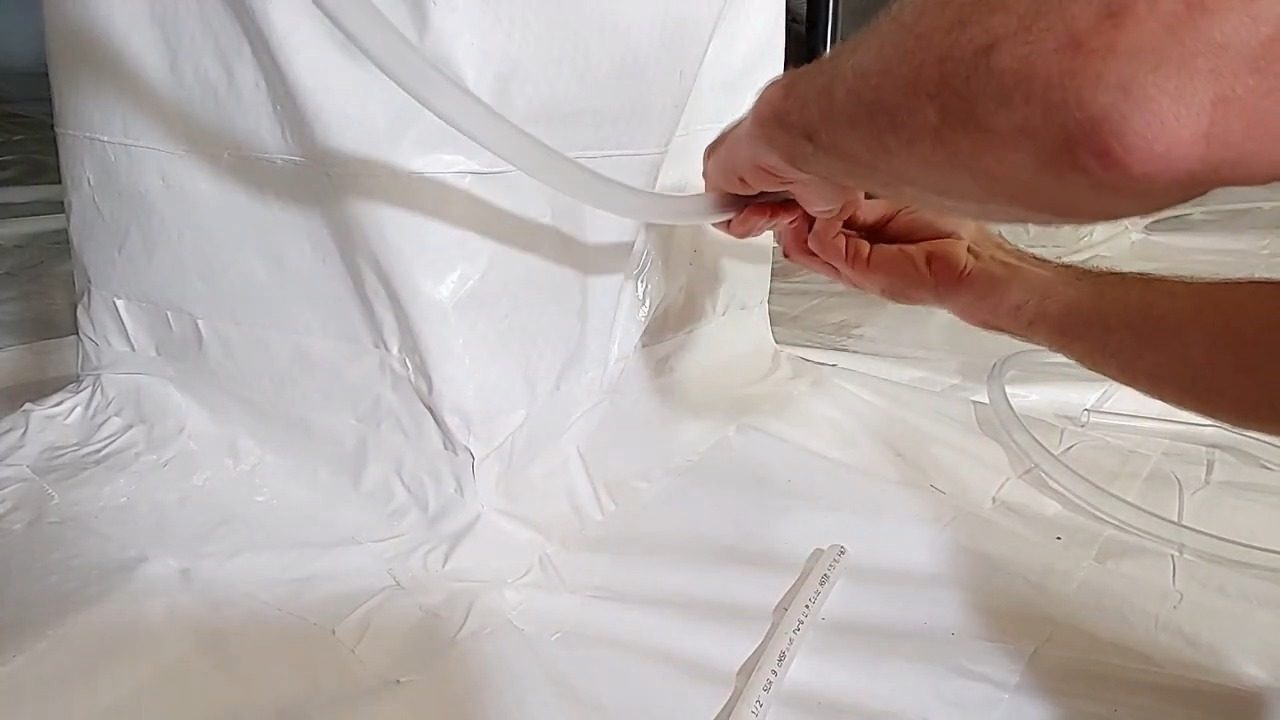 Sealing a white vapor barrier around a crawl space drain tube