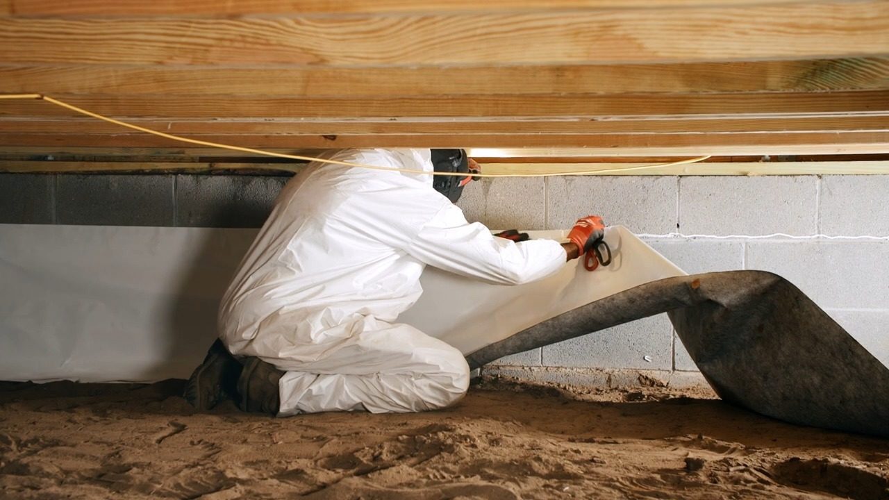 Technician installing a white liner along a crawl space wall